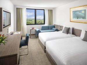 een hotelkamer met twee bedden en een stoel bij Novotel Bangkok Bangna in Bangna