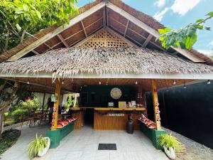 a restaurant with a thatched roof with a clock at Nautilus Hostel & Hammocks in Panglao Island