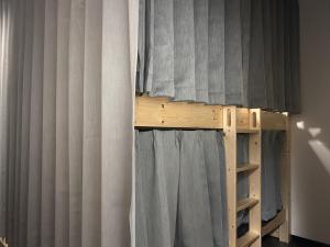 宫古岛女性専用 dormitory all good的一张带灰色窗帘和梯子的双层床 更多6张照片