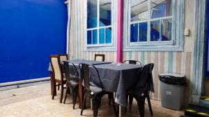 een tafel en stoelen met een blauwe muur en een raam bij Casa de Huéspedes Providencia Baquedano in Santiago