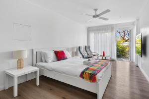 a white bedroom with a bed and a window at Garigal Retreat with Pool access and EV Station in Forestville +23 photos