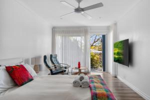 a white bedroom with a bed and a table and chairs at Garigal Retreat with Pool access and EV Station in Forestville