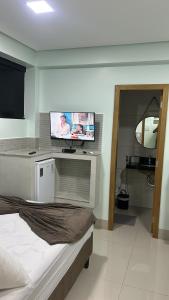a bedroom with a bed and a flat screen tv at POUSADA DA MAGA in Chapada dos Guimarães