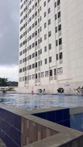 een groot gebouw met een zwembad ervoor bij Corner High floor 2BR apartment Batam in Nagoya