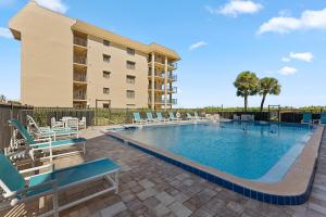 een zwembad met ligstoelen naast een gebouw bij Canaveral Sands 4202 in Cape Canaveral