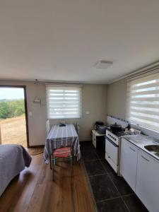 a kitchen with a table and a sink and a stove at Cabaña 2 a 4 personas in Carahuo
