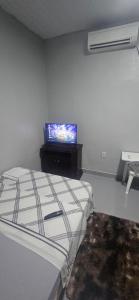 a bedroom with a bed and a tv on the wall at Boa opção in Manaus