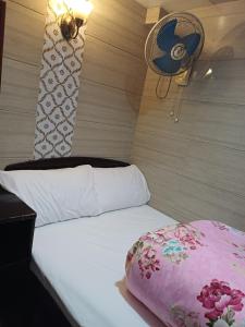 a bedroom with a bed with a pink pillow and a fan at DREAMNEST GUESTHOUSE Tsim Sha Tsui in Hong Kong