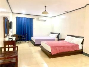 a hotel room with two beds and a table and a desk at Shine Hotel in Sampong