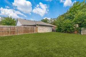 ein Hinterhof mit einem Zaun und grünem Gras in der Unterkunft Historic Downtown McKinney 3BR in McKinney