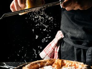 iemand die een tang vasthoudt naast een pizza bij Hotel Mercure Roma Corso Trieste in Rome