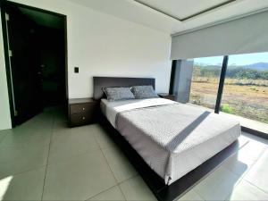 ein Schlafzimmer mit einem Bett und einem großen Fenster in der Unterkunft Playa Potrero in Potrero