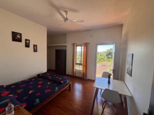 een slaapkamer met een bed, een bureau en een raam bij Empra Exotica in Madikeri