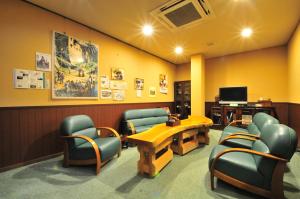 een wachtkamer met stoelen en een tafel en een tv bij uedaonsen jukyuan in Ueda