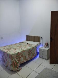 een slaapkamer met een bed en een nachtkastje met een paars licht bij Ambiente Família e acolhedor in Porto Seguro