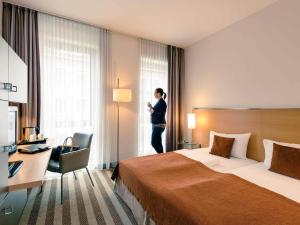 a woman standing in a hotel room looking out the window at Mercure Hotel Aachen Am Dom in Aachen +78 photos