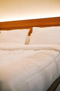 d'un lit non aménagé avec des draps et des oreillers blancs. dans l'établissement Djayati Loft Stay, à Timuran
