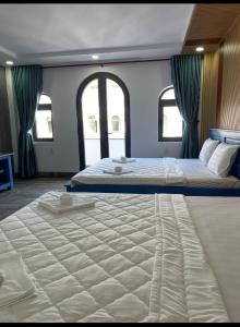 een groot wit bed in een kamer met ramen bij Hotel CÂY THỊ - Tây Ninh in Tây Ninh