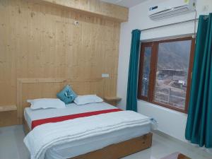 a bedroom with a large bed with a window at Hotel Dharam Ganga in Uttarkāshi