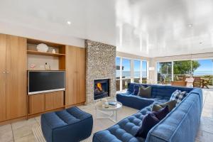 een woonkamer met een blauwe bank en een open haard bij Louttit Bay Lookout in Lorne