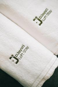 Deux serviettes blanches avec les mots joyeux anniversaire dans l'établissement Djayati Loft Stay, à Timuran