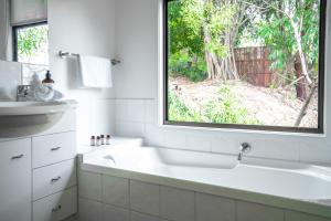 een badkamer met een bad, een wastafel en een raam bij Nebesa in Mudgeeraba