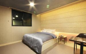 a bedroom with a bed and a window and a table at SU Motel in Gumi
