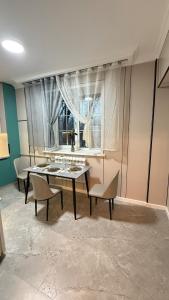 a dining room with a table and chairs and a window at Kurmangazy in Zhezdi