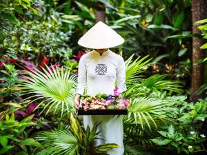 a woman wearing a hat holding a tray of fruit at La Veranda Resort Phu Quoc - MGallery in Phu Quoc