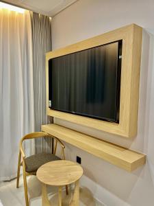 een televisie aan een muur in een kamer met een stoel bij Busan Seomyeon Nestly Hotel in Busan
