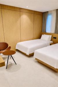 een hotelkamer met twee bedden en een stoel bij Busan Seomyeon Nestly Hotel in Busan +23 foto's