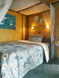 a bedroom with a bed with a blue and white comforter at Yoschi's Hotel Bromo in Ngadisari