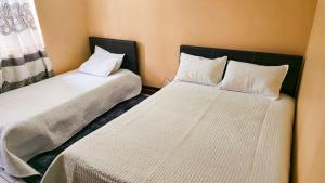 a bedroom with two beds with white sheets at SDG Lodge in Blantyre