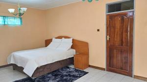 a bedroom with a bed and a wooden door at SDG Lodge in Blantyre