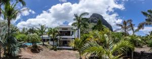 una casa con palme e una montagna sullo sfondo di The Villa - Le Morne - Kite, Golf & Beach a Le Morne