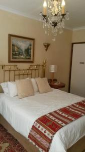 a bedroom with a large white bed with a chandelier at Belle Vue Guesthouse in Hermanus