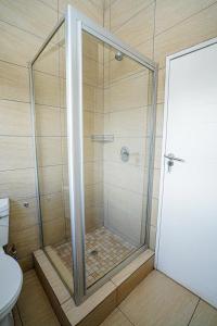 una ducha con puerta de cristal en un baño en Royal Palm, en Mokopane