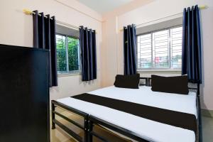 um quarto com uma cama grande e cortinas azuis em Hotel O by OYO DA Guest Home em Jādabpur