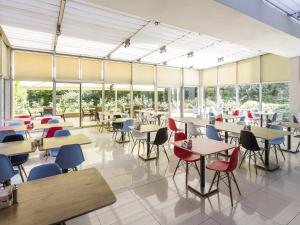 a cafeteria with tables and chairs and windows at Ibis Gaziantep in Gaziantep