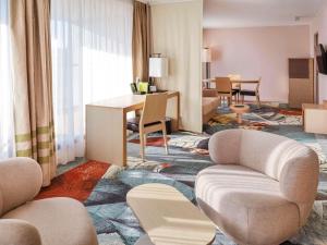 Mercure Amiens Cathédrale في أميان: غرفة معيشة مع كراسي وطاولة في غرفة فندق