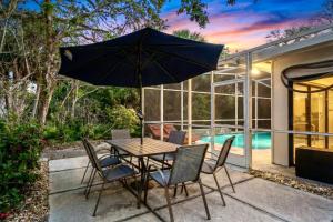 a table and chairs with an umbrella on a patio at Toes in the Water - Pool Home on Siesta Key in Siesta Key