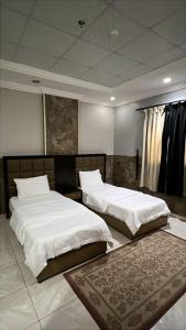 two beds in a large room with a rug at شموخ العلياء للشقق المخدومة in Al Jith