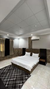 a bedroom with a large white bed and a black rug at شموخ العلياء للشقق المخدومة in Al Jith