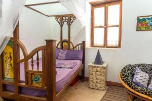 a bedroom with a wooden bed with purple sheets at Ella's Swahili House in Bagamoyo