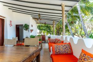 a dining room with a table and chairs and palm trees at Ella's Swahili House in Bagamoyo