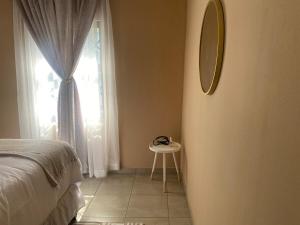 une chambre avec un lit, un miroir et un tabouret dans l'établissement Cozy Haven in Manzini, à Manzini
