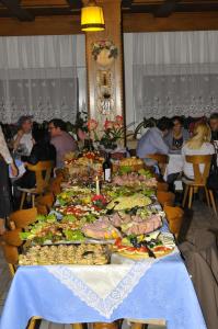 een lange tafel vol eten met mensen die er omheen zitten bij Pension Resy in Auna di Sopra