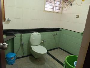 a bathroom with a toilet in a green and white room at MANTRAs in Mysore