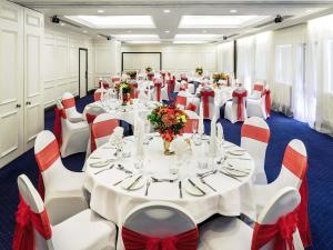 a banquet hall with white tables and red and white chairs at Mercure Swansea Hotel in Swansea