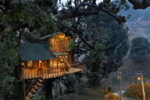 uma casa na árvore com um deque numa árvore em Rumsu Tree House by SLC em Nagar